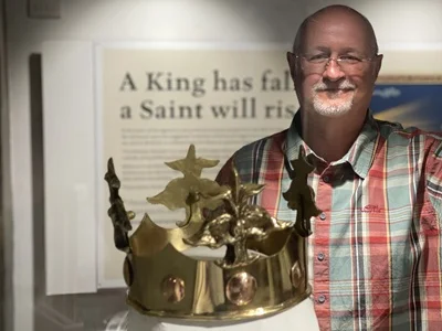 A gold replica crown of St Edmund in a display case at Moyse's Hall, with Cllr Ian Shipp standing behind it